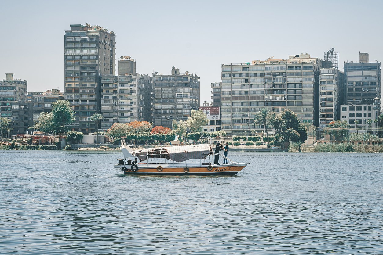 boat with tourists on a river walk sails along the Nile River in the center of Cairo among the skyscrapers and attractions.