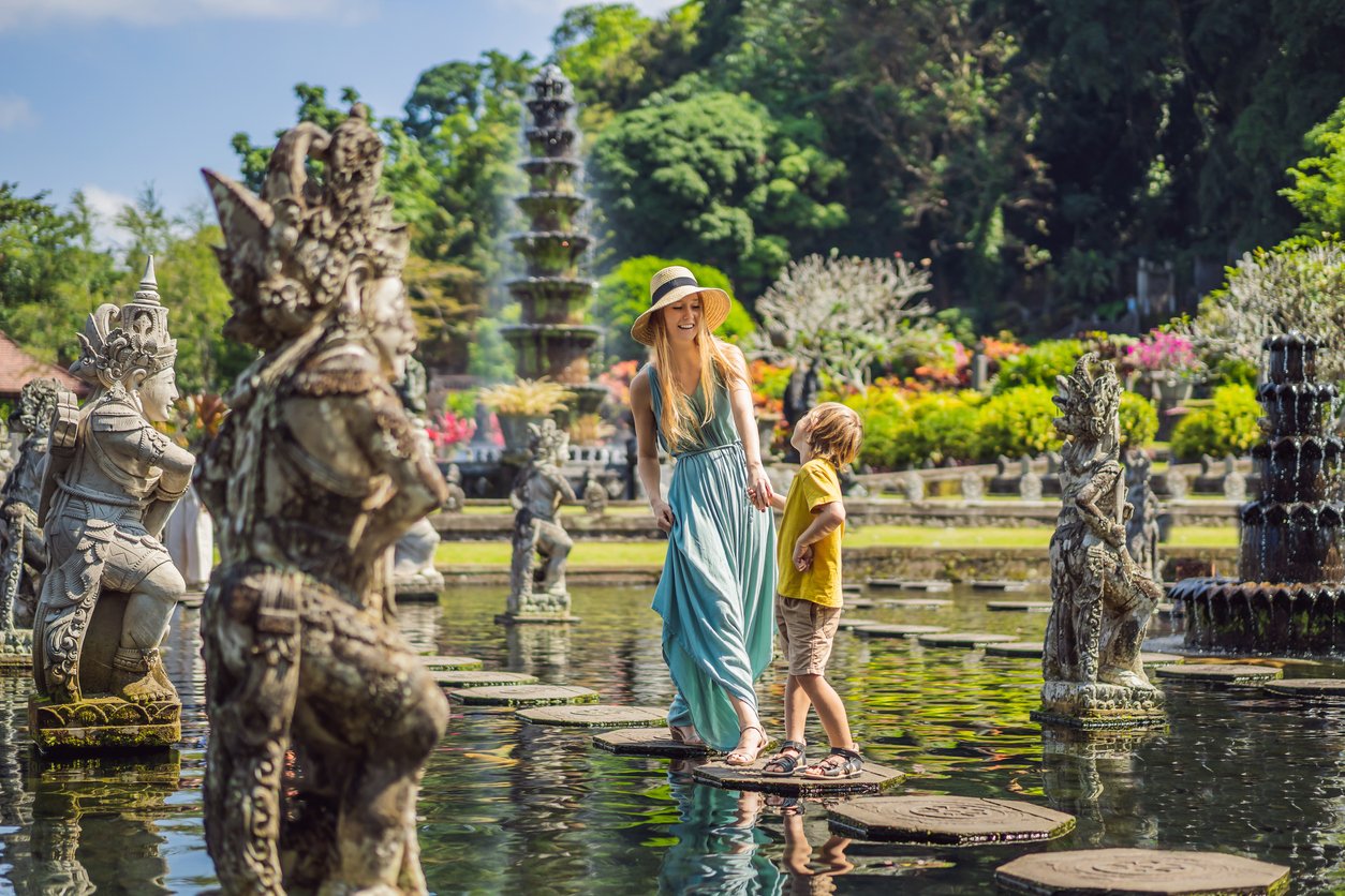 Mom and son tourists in Taman Tirtagangga, Water palace, Water park, Bali Indonesia. Traveling with children concept. Kids friendly place