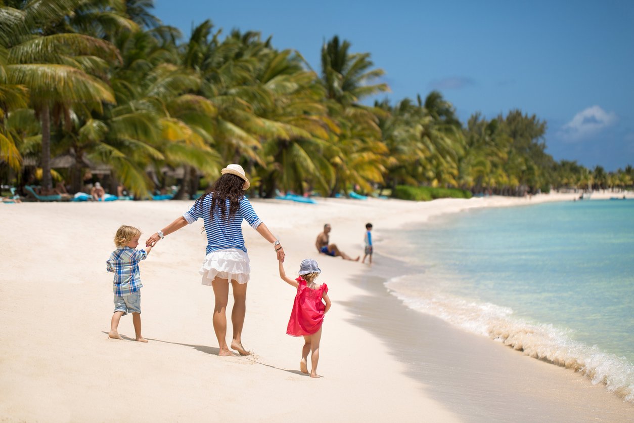 Beautiful mother, son and daughter walking on the beach of the Indian ocean.